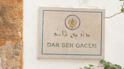 Plaque murale indiquant 'DAR BEN GACEM' avec des motifs décoratifs sur un mur blanc.